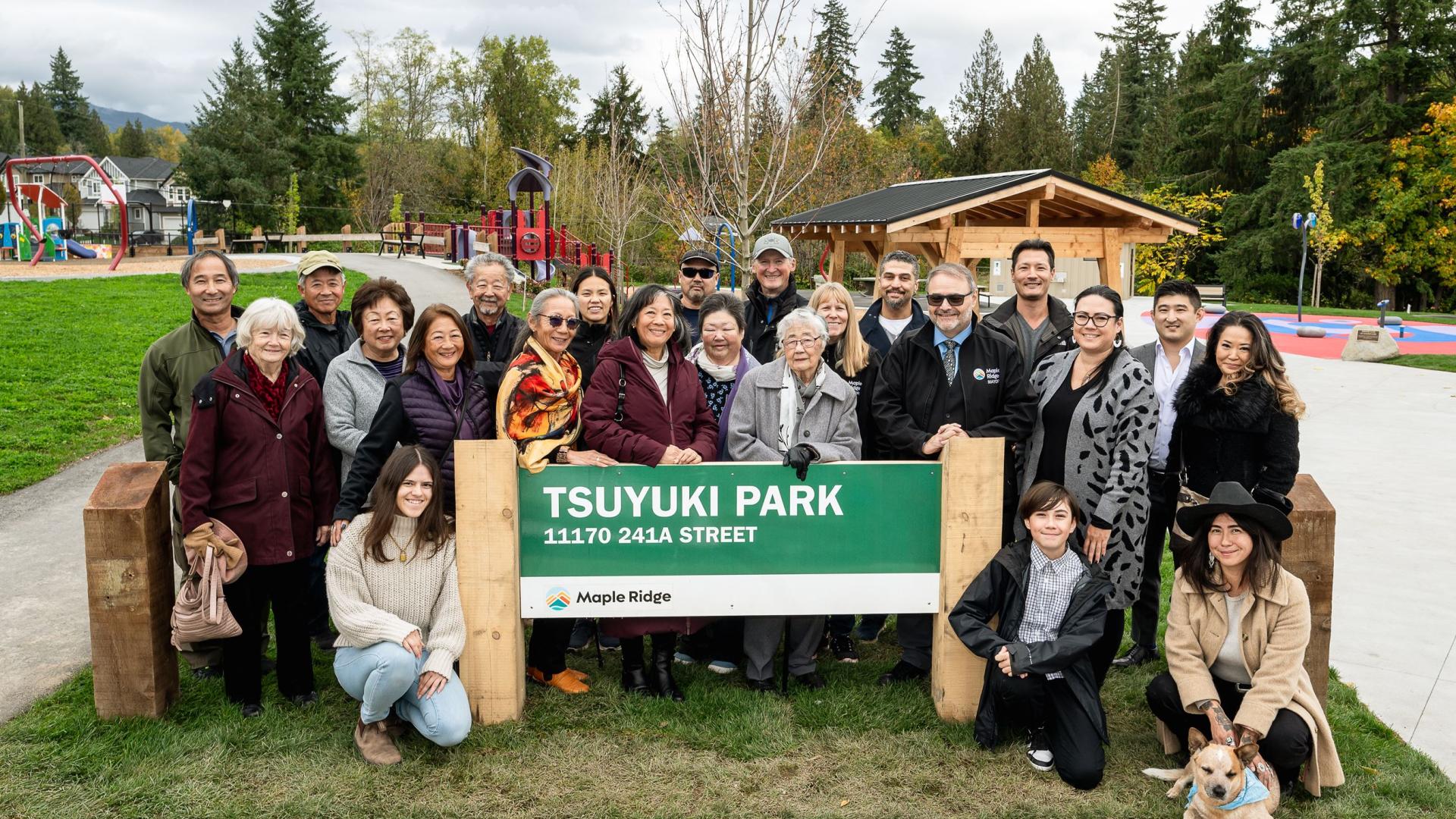 A group of people smiling in front of Tsuyuki Park sign