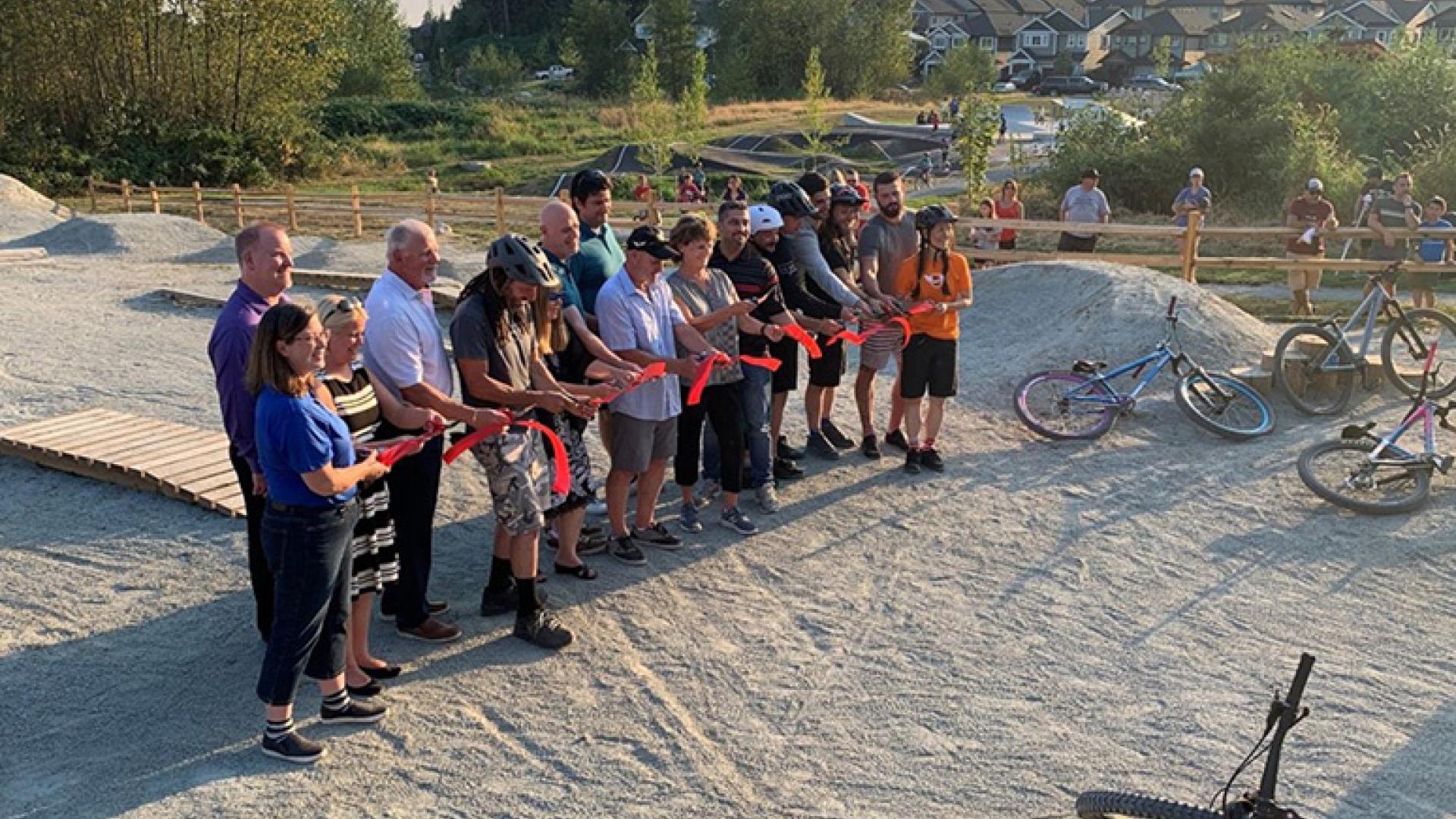 Bikers outside Jordan McIldoon Legacy Bike Skills Park cutting ribbon
