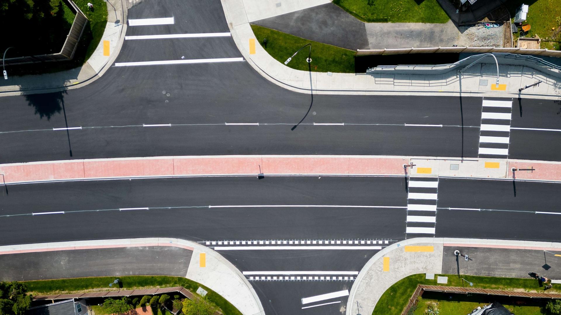 A view from directly above Abernethy Way, with two crosswalks going from the side walk to the centre median, not directly lined up with each other.