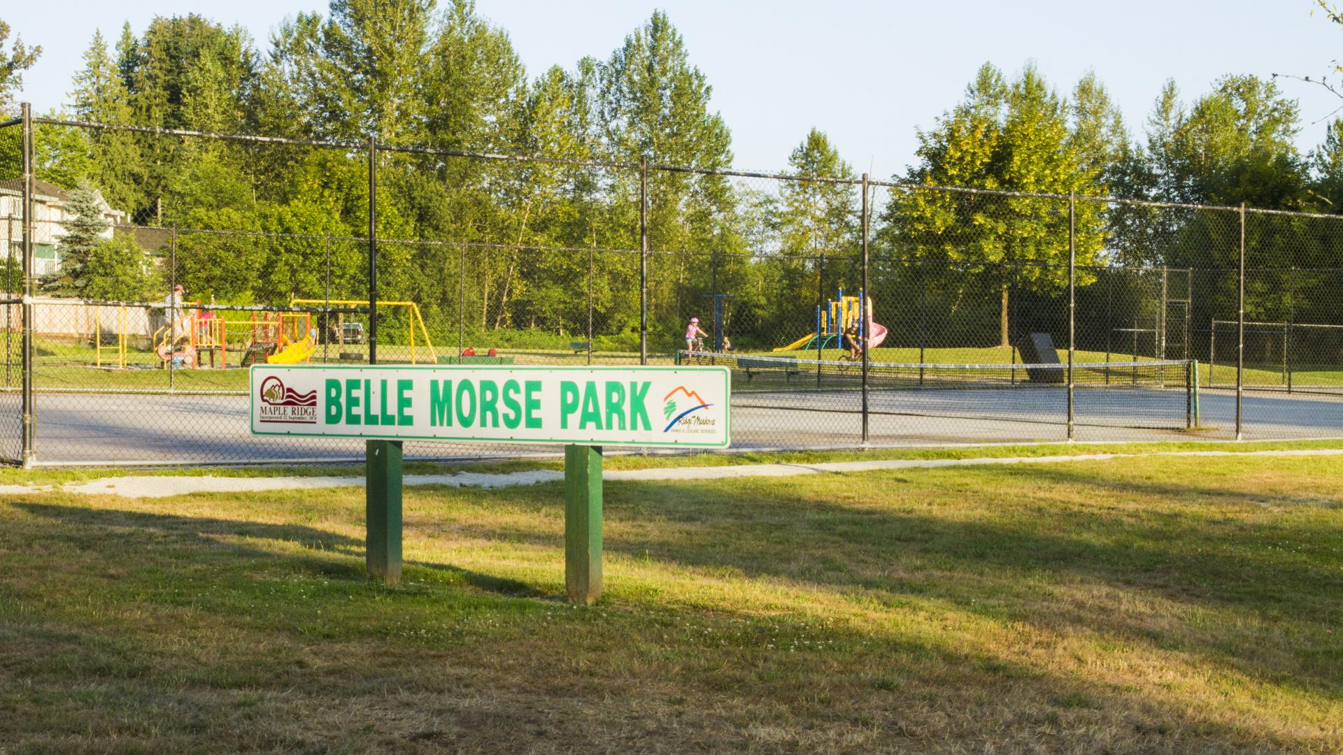 The Belle Morse Park sign sits on a patch of grass near the basketball court.