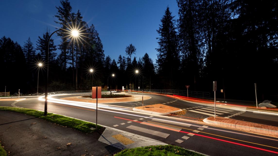 A long exposure of a new, single lane roundabout at night. Lines of light from vehicles wrap around the roundabout.