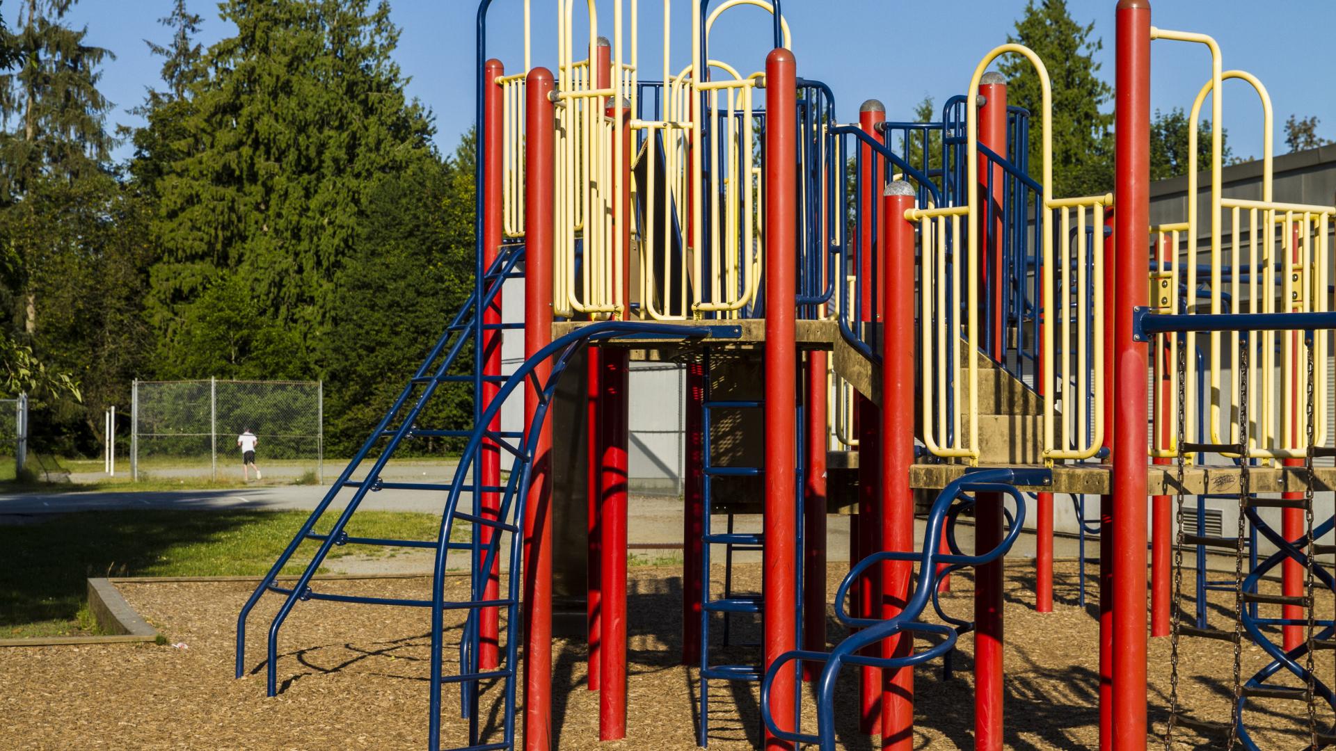 A red and navy playground with multiple twisty metal stairs for climbing up it.