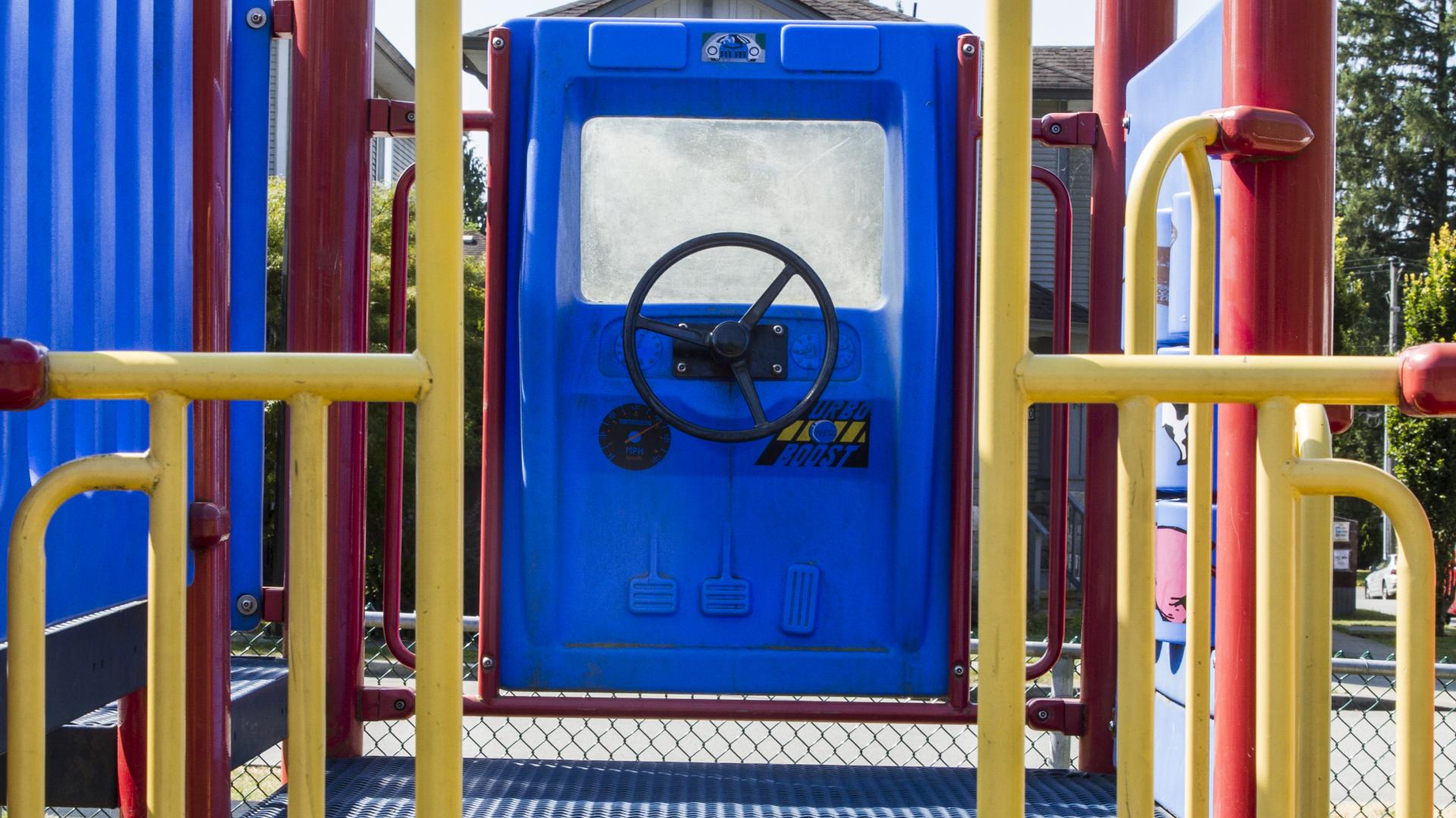 The top level of a playground with a steering wheel mounted on the far wall.
