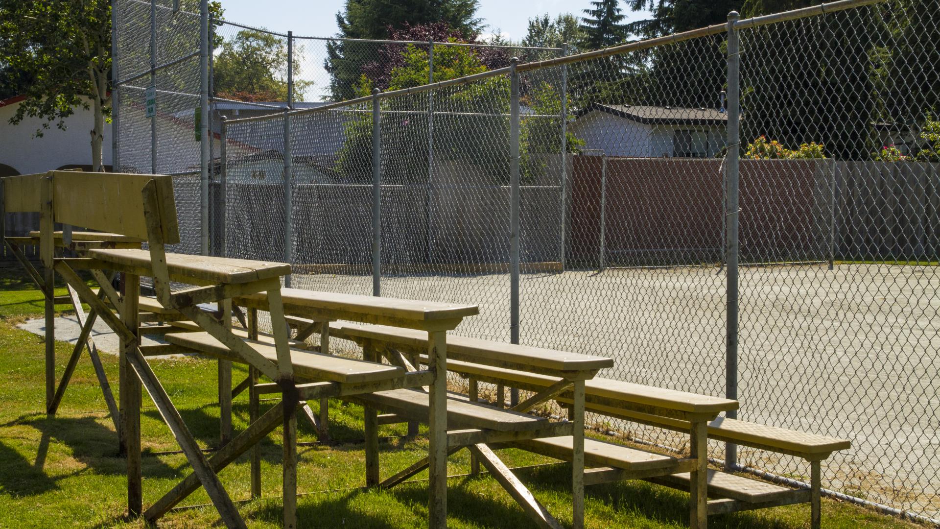 Bleachers on the outside of a fence around a baseball diamond. 