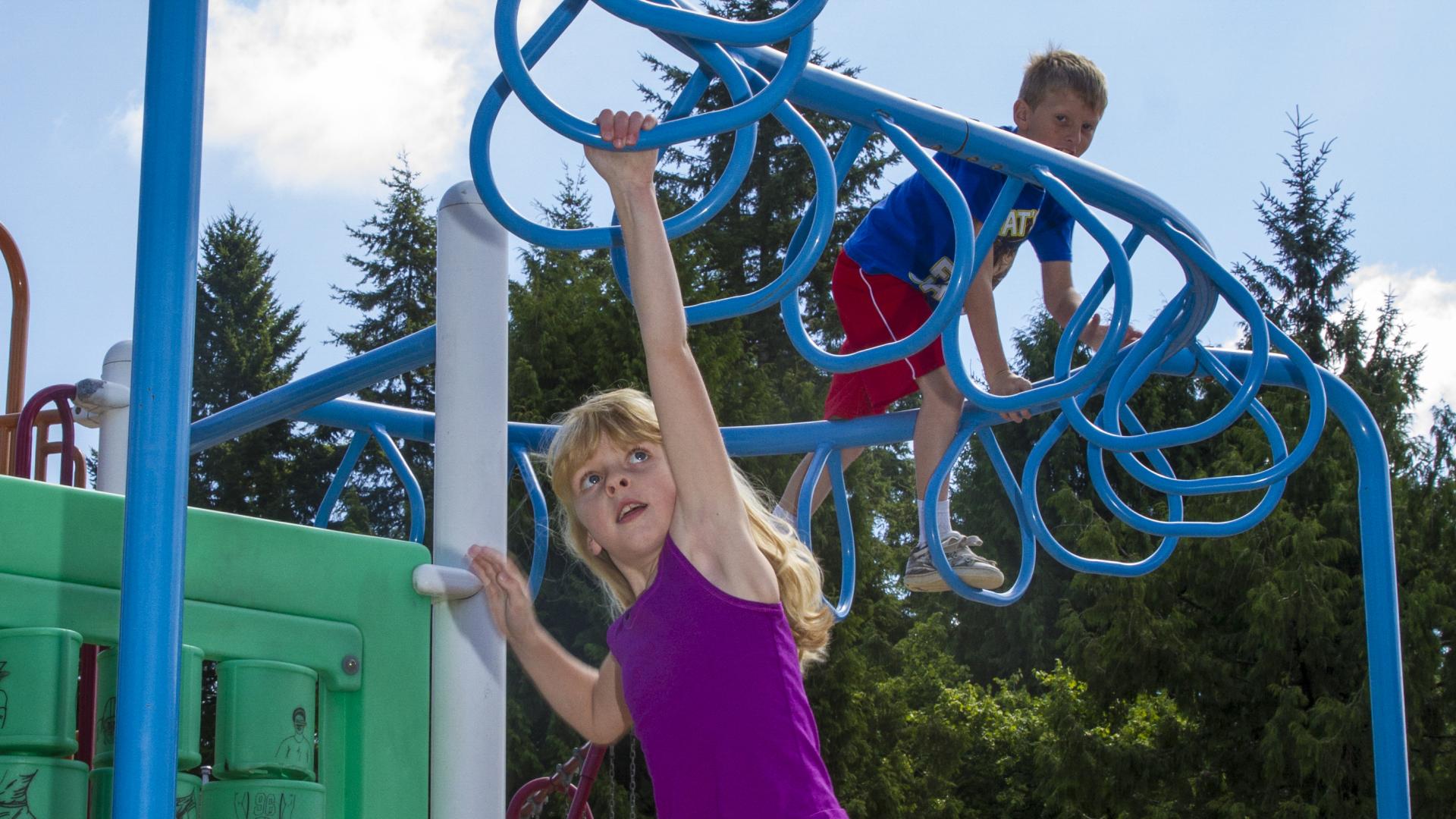 A young girl is mid swing on the monkey bars.