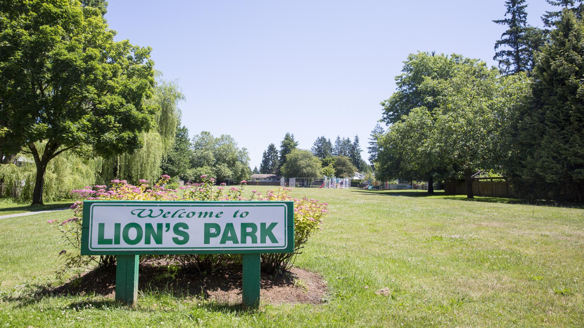 The Lion's Park sign sits on the edge of a large grass field.