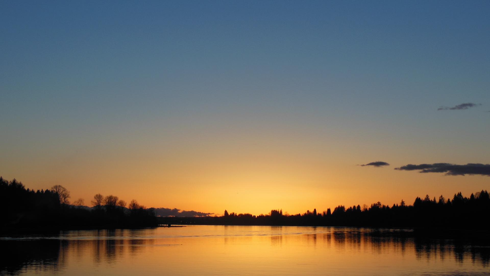 The sunset is reflected in the calm waters of the Fraser River at the Port Haney Wharf.