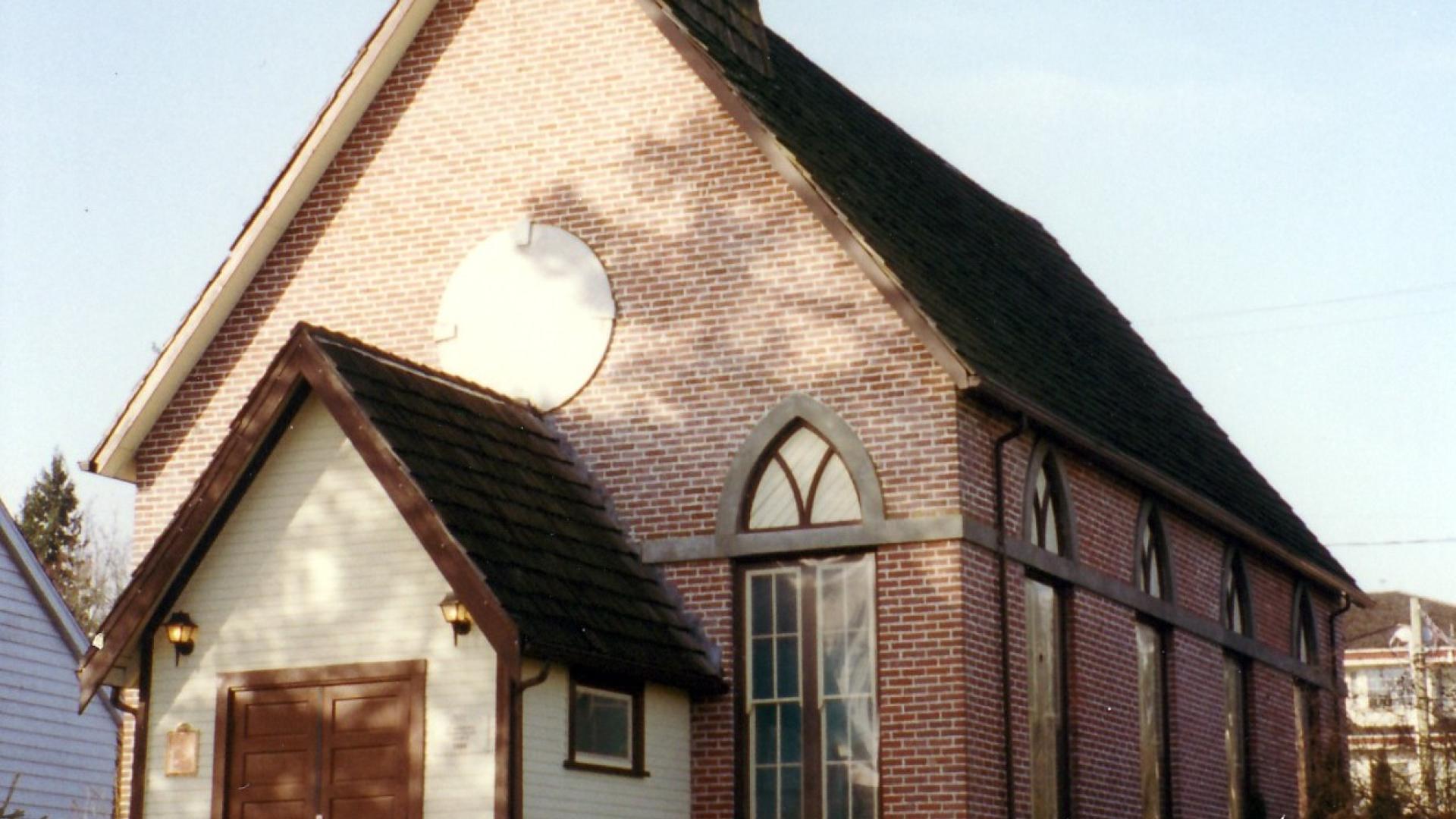 Exterior of St. Andrew's Heritage Church. The church is a small brick building with two large wooden doors at the front.