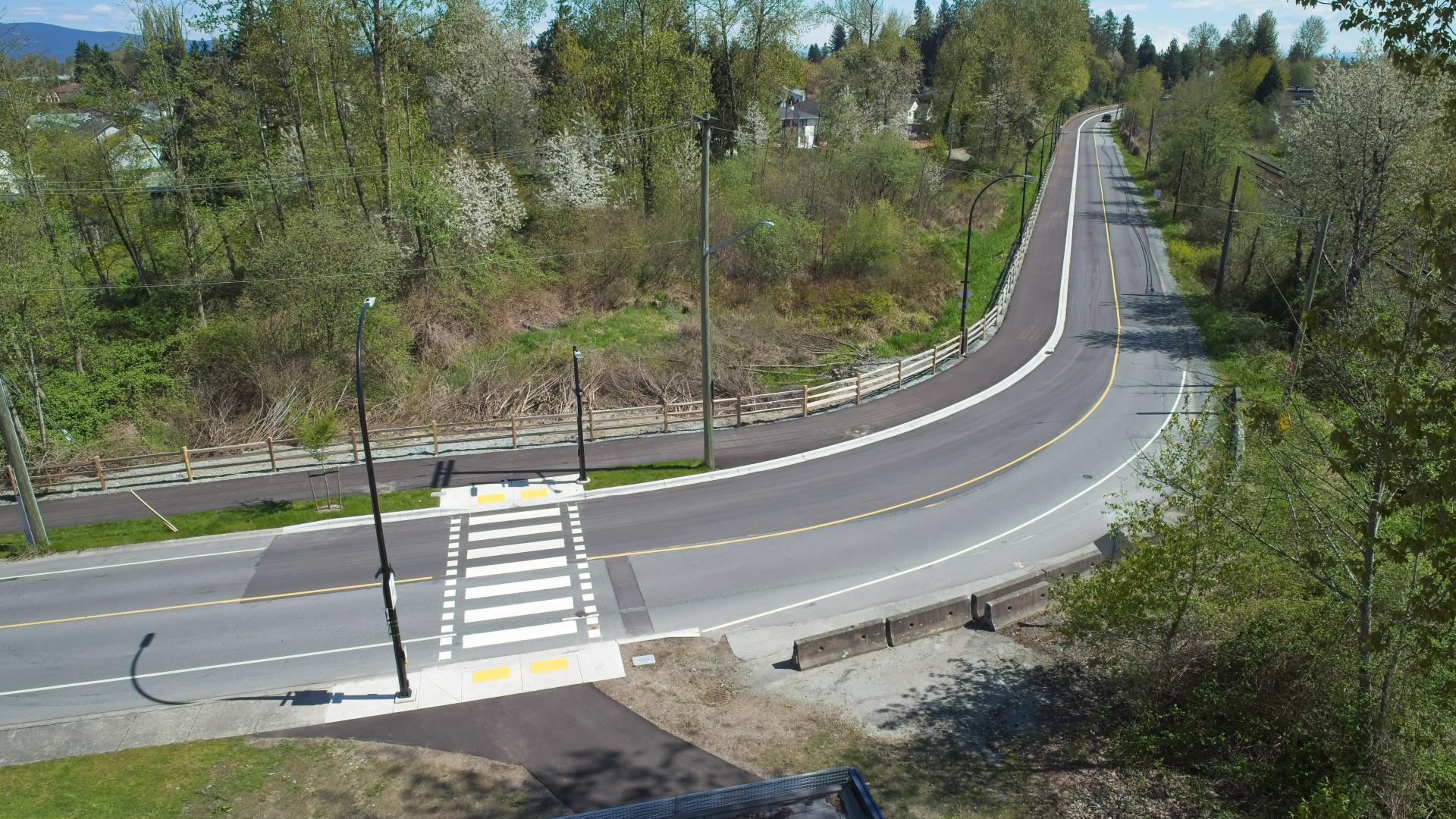 A crosswalk runs from the Hammond Multi-Use Path to the other side of the street just before a bend in the road.
