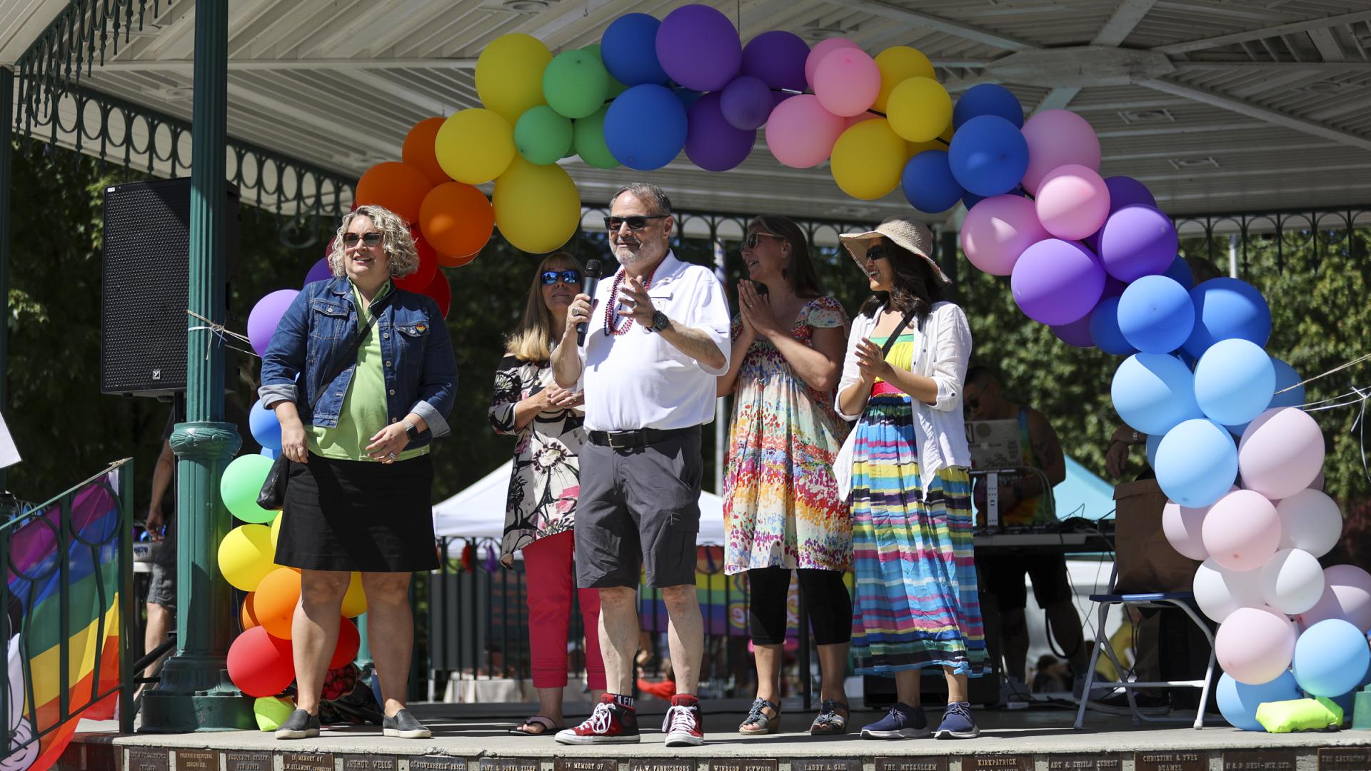 People standing with the Mayor onstage giving a speech at Pride in the Park