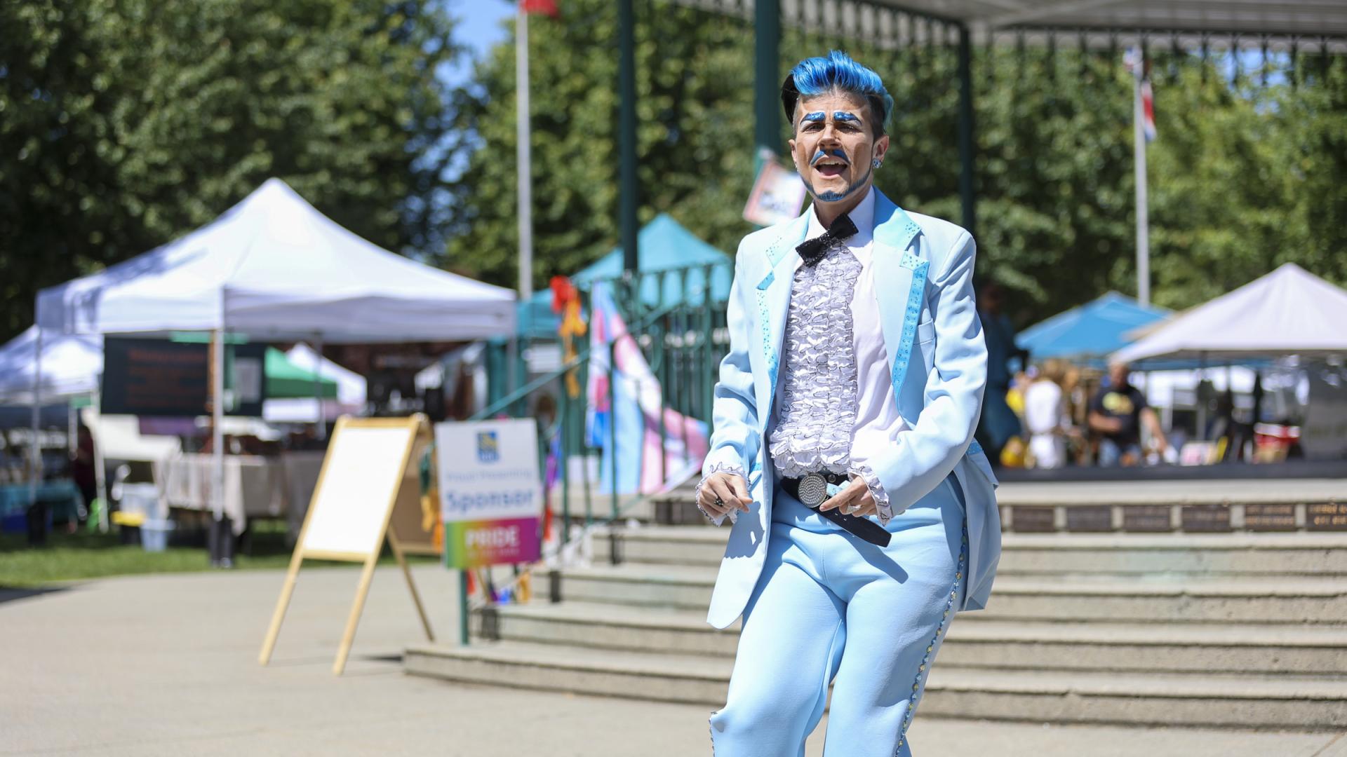 Drag king dawning a blue suit and glitter beard performing for the crowd at Pride in the Park
