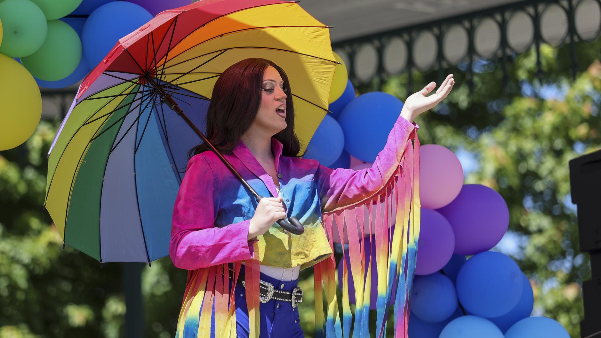 Drag queen performing on stage while dawning rainbow attire at Pride in the Park