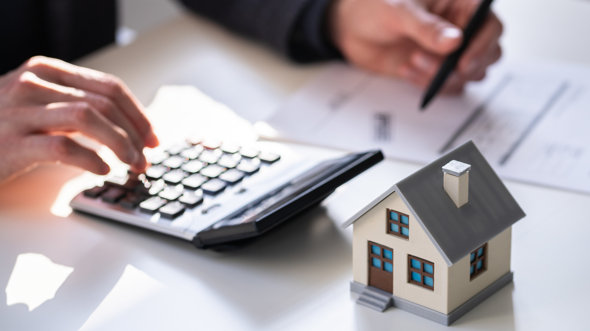 little wooden house on the table in front of calculator
