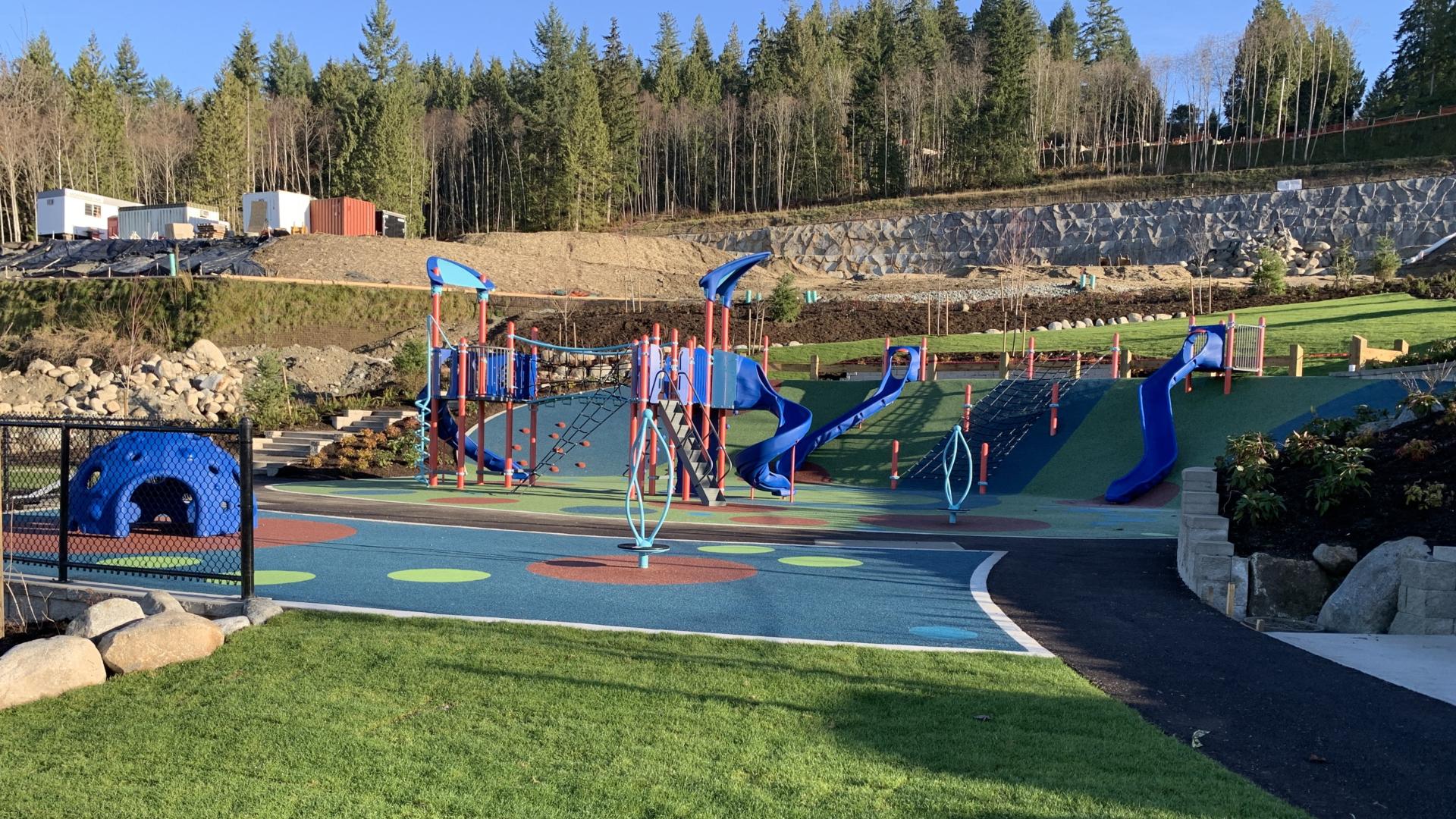 Playground on hill with colourful rubber surfacing, many slides and play structure