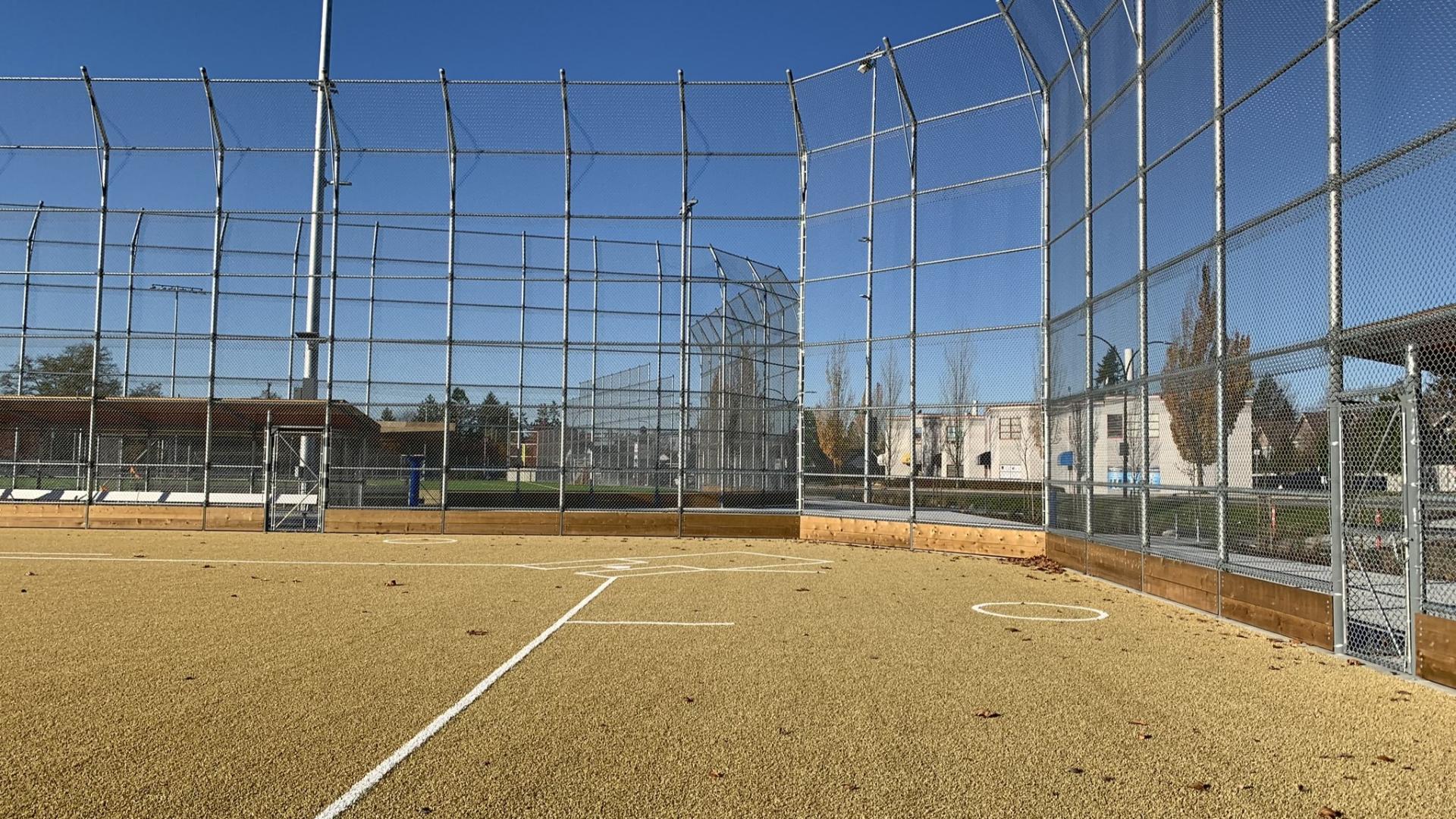 Synthetic baseball diamond with tall chain link fence