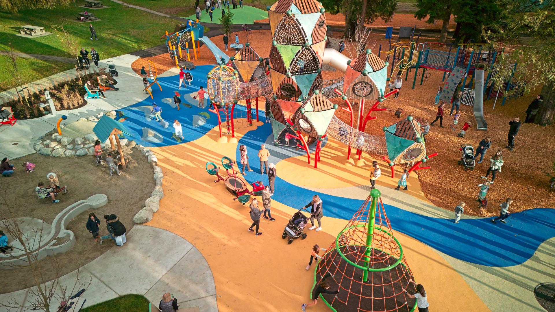 aerial photo of playground with lots of children and adults and featuring tall climbing tower 