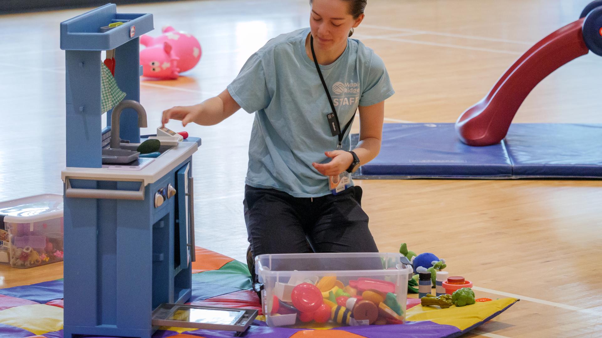 A Children's Staff Person Organizing Toys for Little Ones