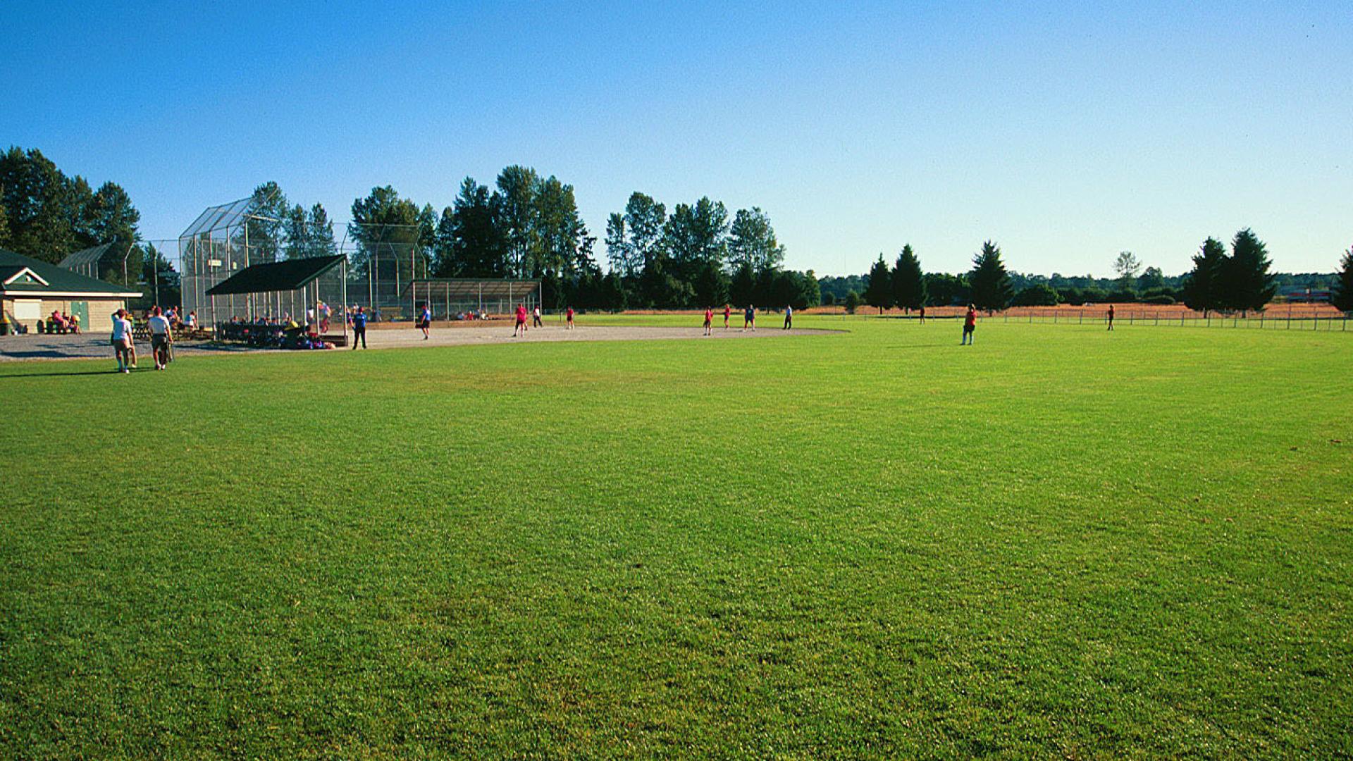 A baseball diamond in sports complex field on a clear blue sky day