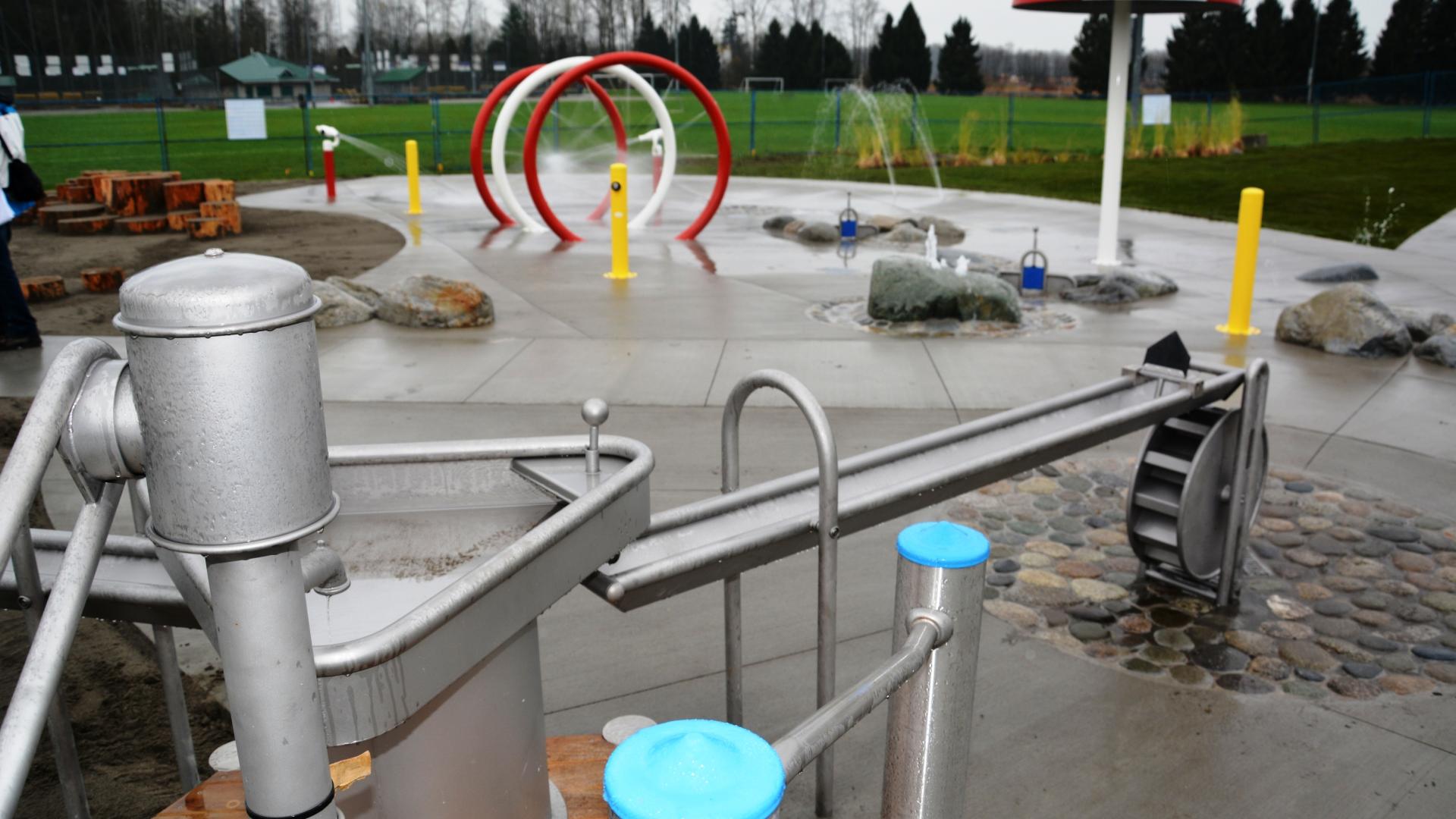 Small spray park with water play table in foreground