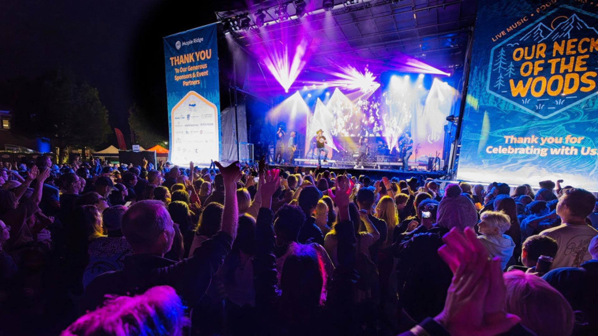 A crowd gathers around a stage at the 2024 Our Neck of the Woods while Aaron Pritchett performs..