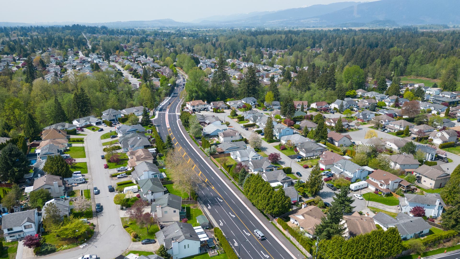 A fresh-paved road winds through a residential area.