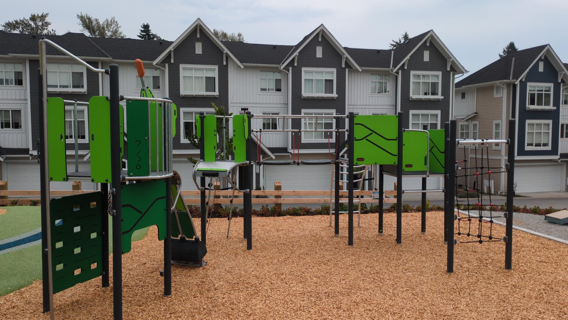 An intermediate play structure with green panels, a cliffrider pivot arm and a climbing rope net