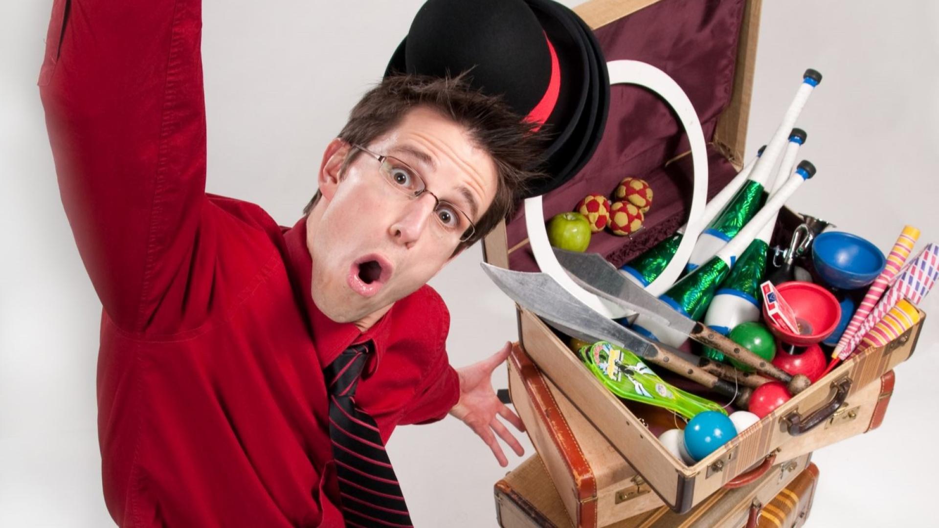 Alex Zerbe showcases the many props in his Zaniac show; including but not limited to: playing cards, batons, balls, an apple, suitcases, juggling knives, and three bowler hats.