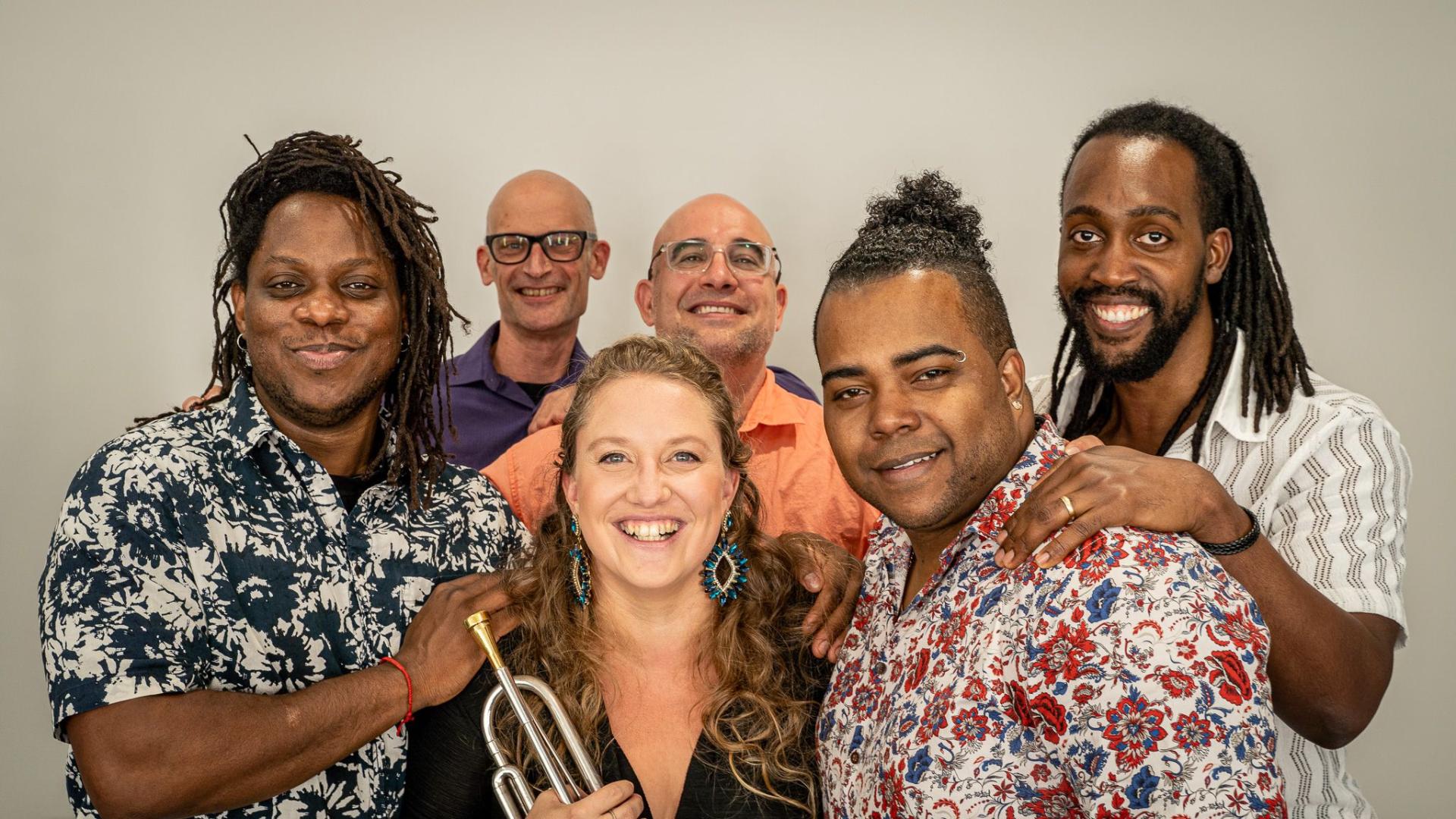 The Rachel Terrien Latin Jazz Quintet smiles at the camera against a neutral background.