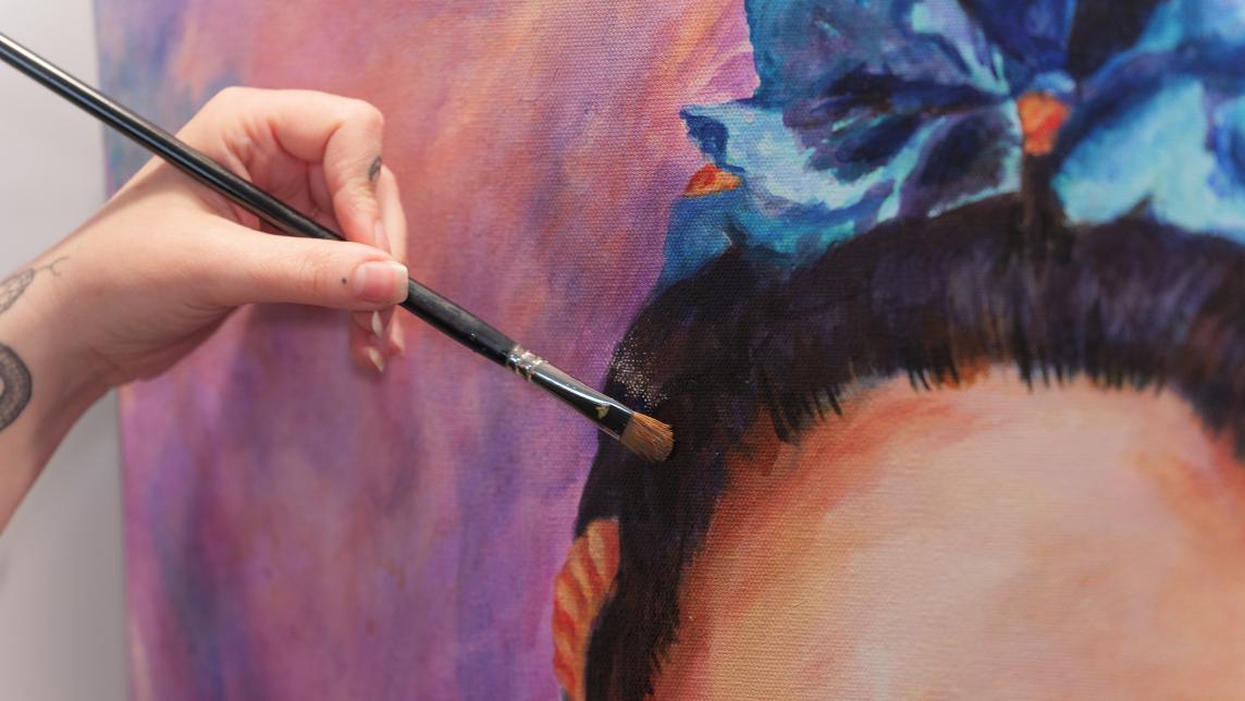 An artist puts the final touches on a painting with a dry paintbrush.