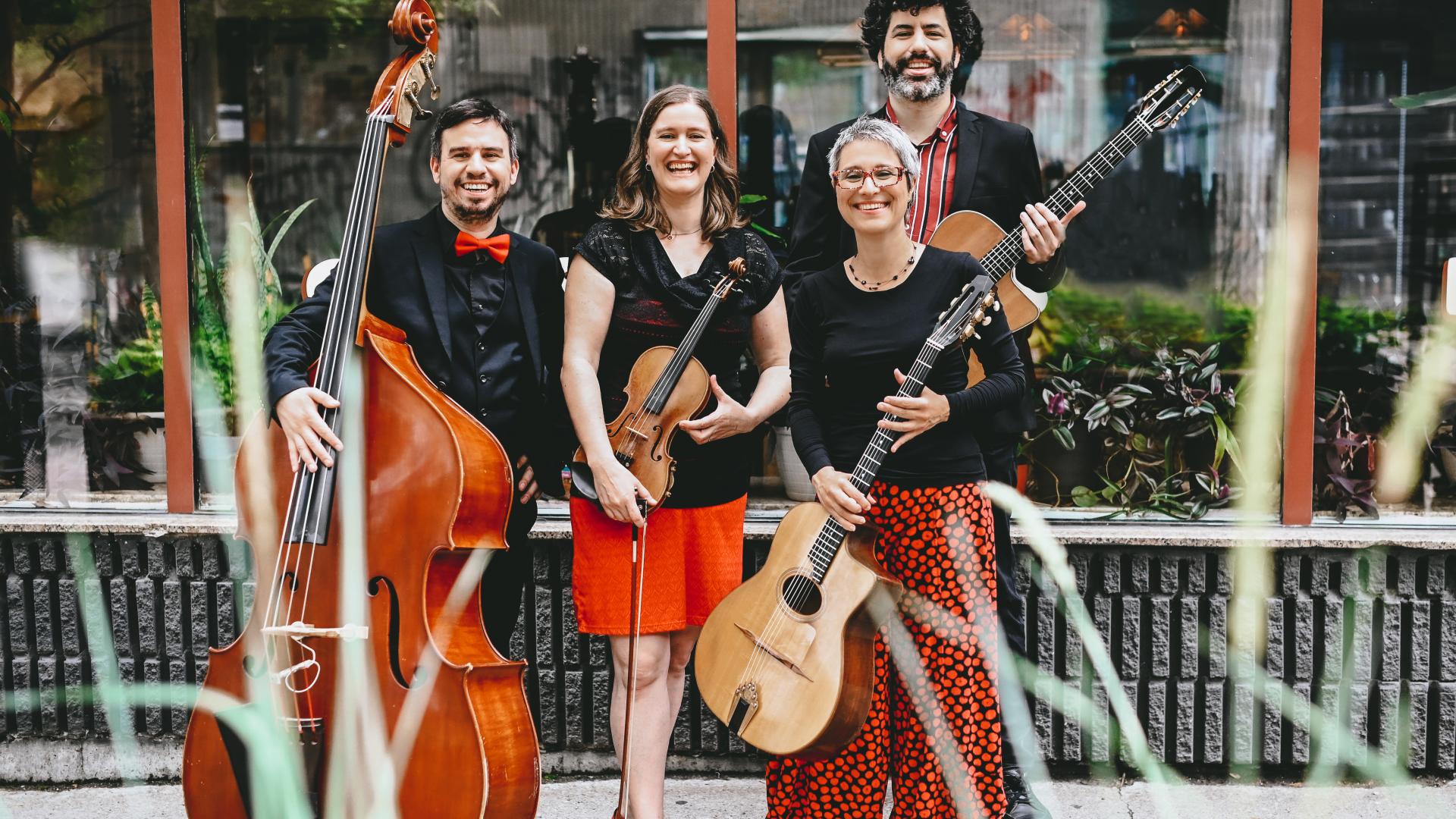 Christine Tassan et Les Imposteurs pose in from of a store with their various stringed instruments, including a guitar, violin and cello. 