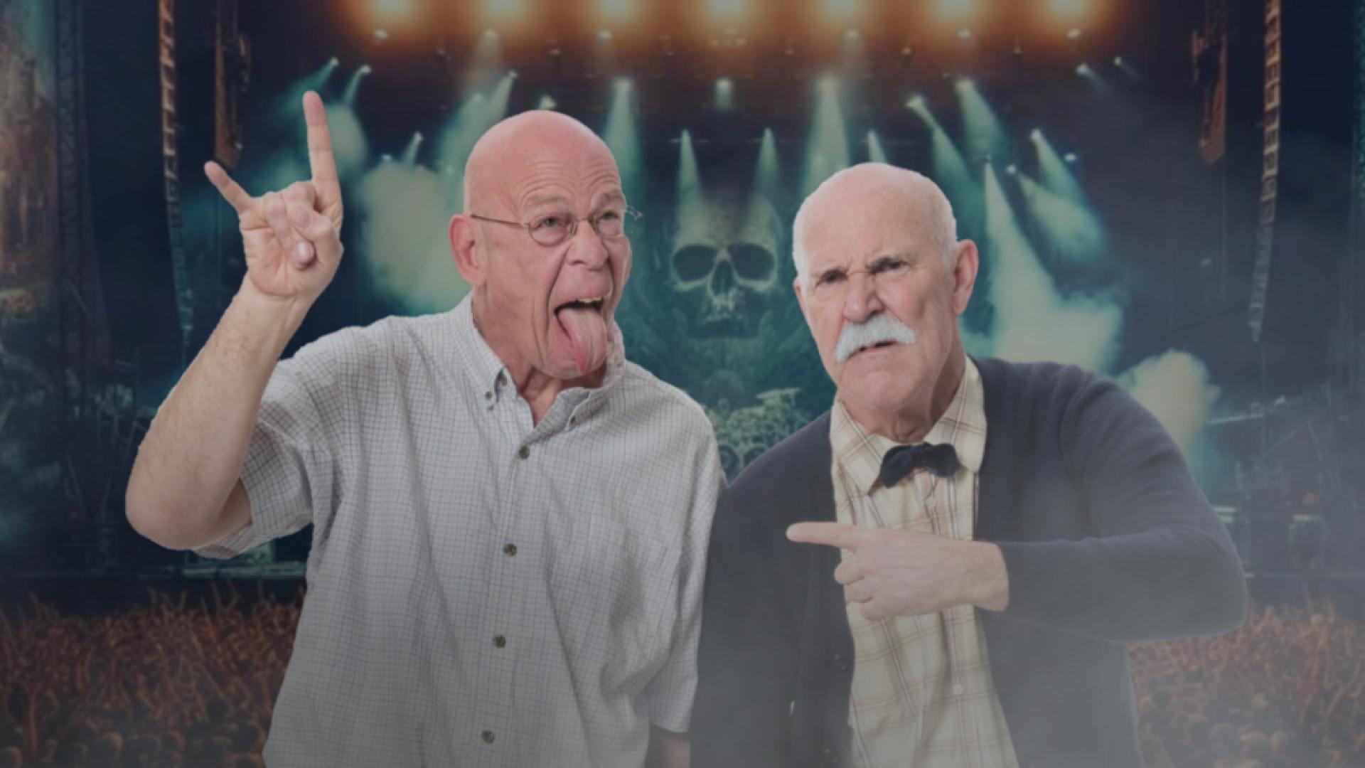 Performer Rob Gee holds up his hand in a "rock on" symbol, and sticks out his tongue while and Jonathon Paterson points to him with a displeased expression.