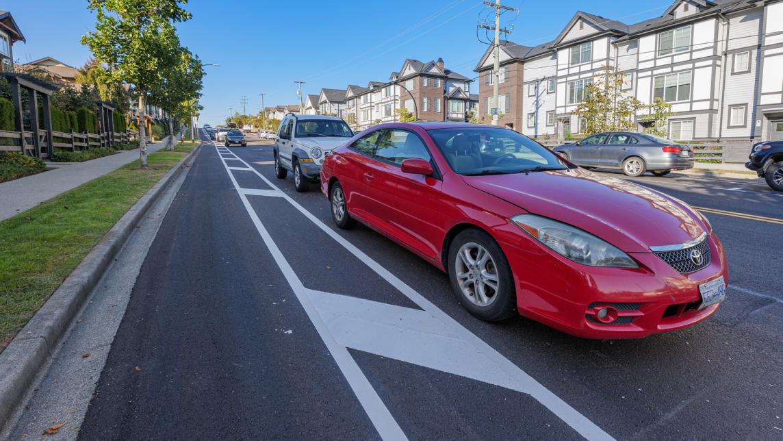 Parked cars next to a painted bike lane