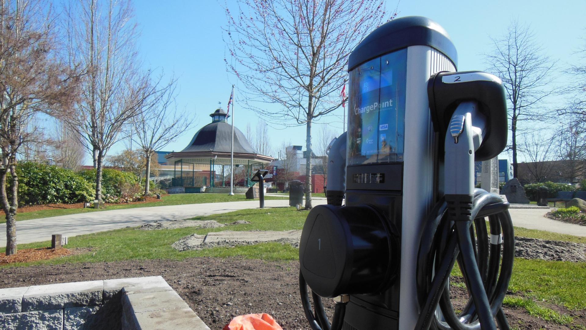 An electric vehicle charging station in Memorial Peace Park, where the bandstand can be seen in the background.