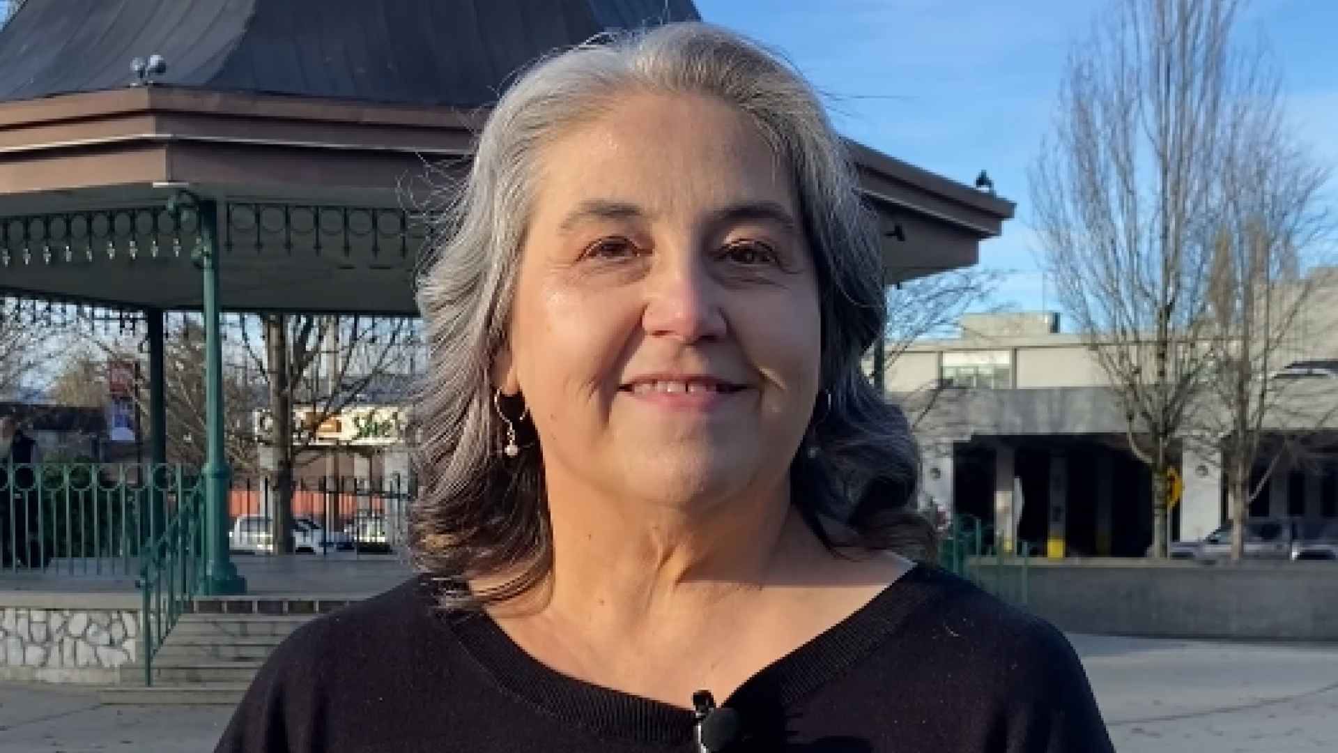A woman smiles at the camera in front of the bandstand at Memorial Peace Park with the caption "The budget guides how we spend and save."