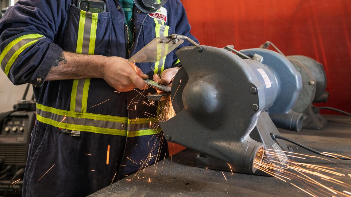 tradesperson grinding metal with sparks flying