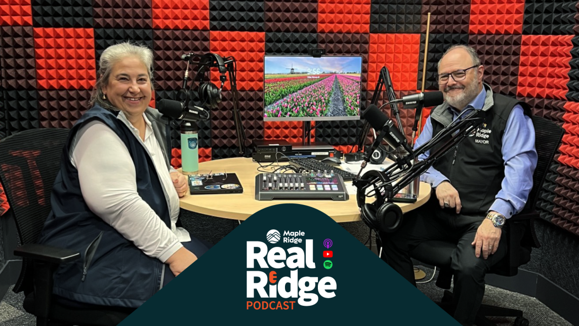 Phil Sanderson sits across the table from Dan Ruimy in a recording studio with black and red checkerboarded soundproof tiles on the wall.