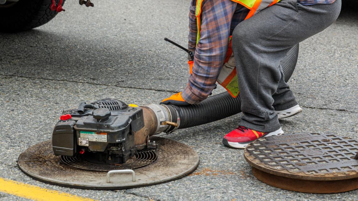 A worker installs a fan on a maintenance hole