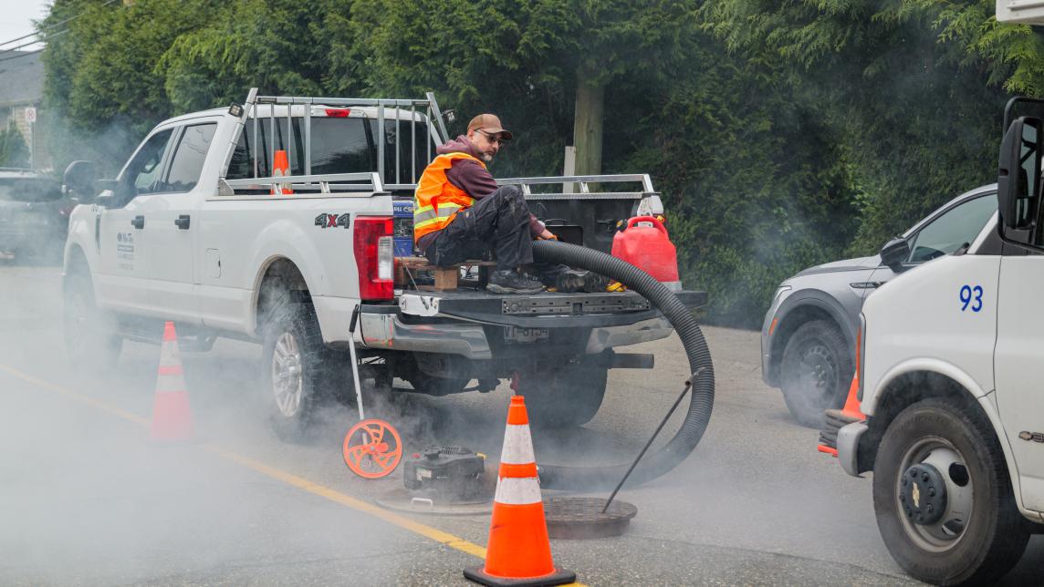 A worker operates fog testing equipment from the back of a truck while fog floats around the area