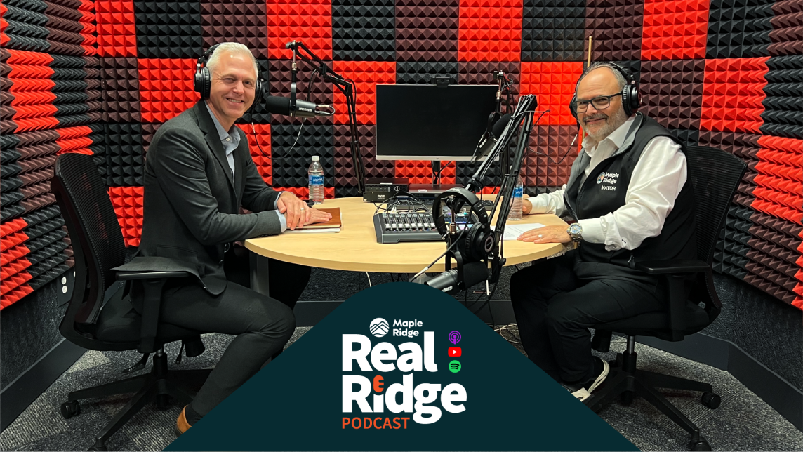 Mayor Dan Ruimy speaks with Kevin Quinn, CEO of Translink in a recording room surrounded by red and black sound-dampening materials.