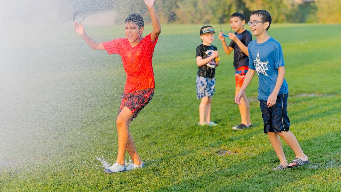 Boys running into sprinkler