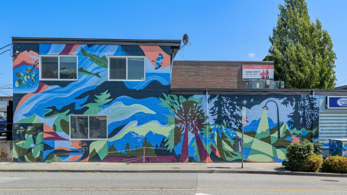 A straight-on view of the mural, showing trees, fish, the Golden Ears mountains and a street light as well as abstractions in blue, green and red.