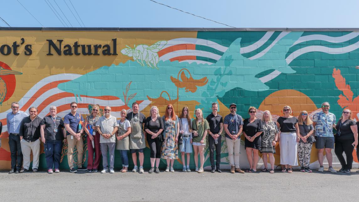 The crowd attending the unveiling gathers in front of the mural. 