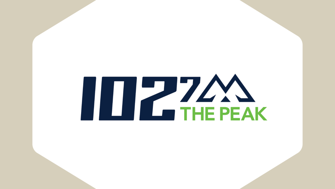 The 102.7 The Peak logo inside an beige frame.