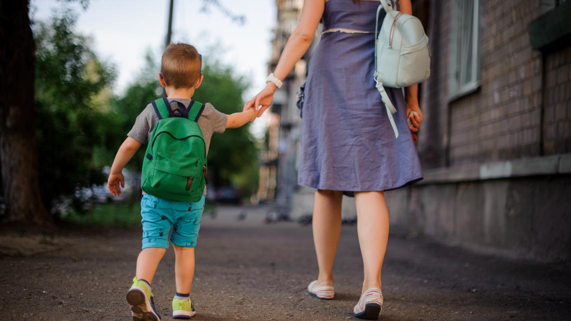 mom and young child walking away from camera