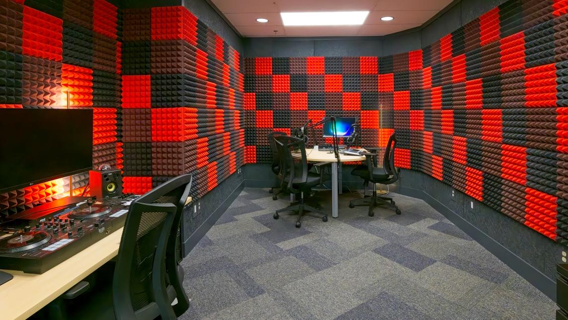 A recording booth with red and black checkerboarded wall soundproofing.
