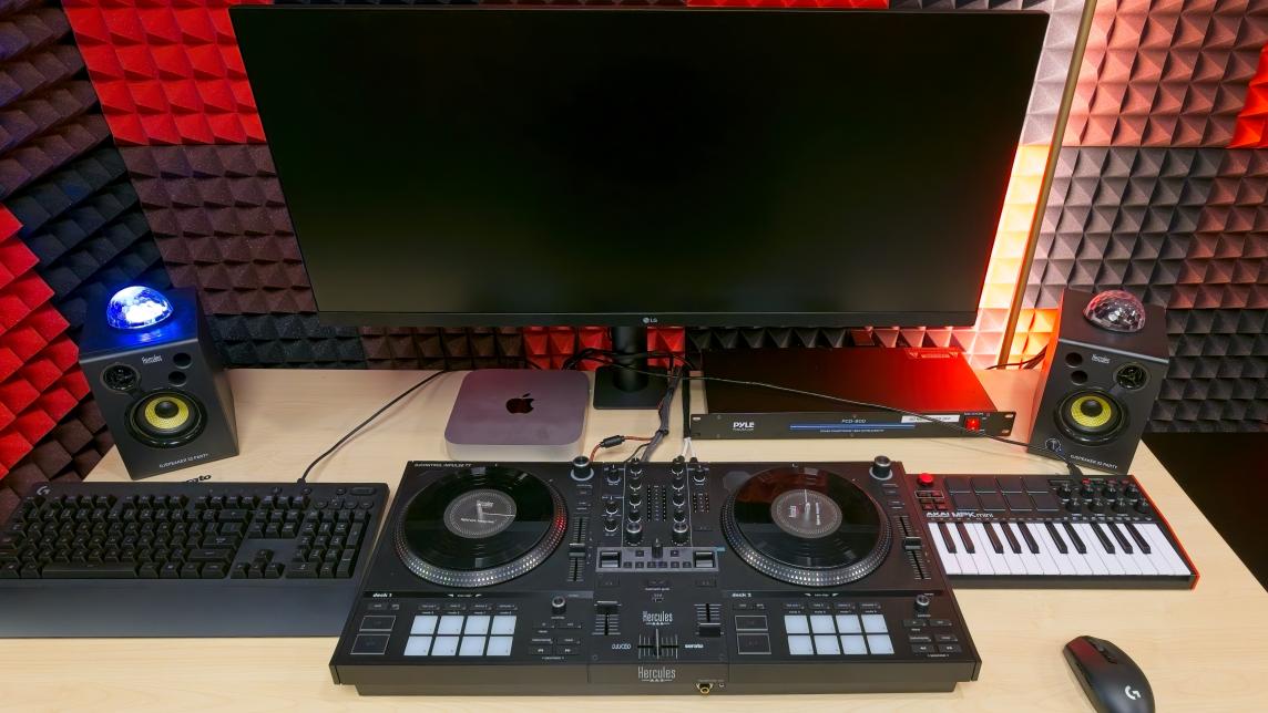 A Disc Jockey set up with computer, turntables, and keyboard.