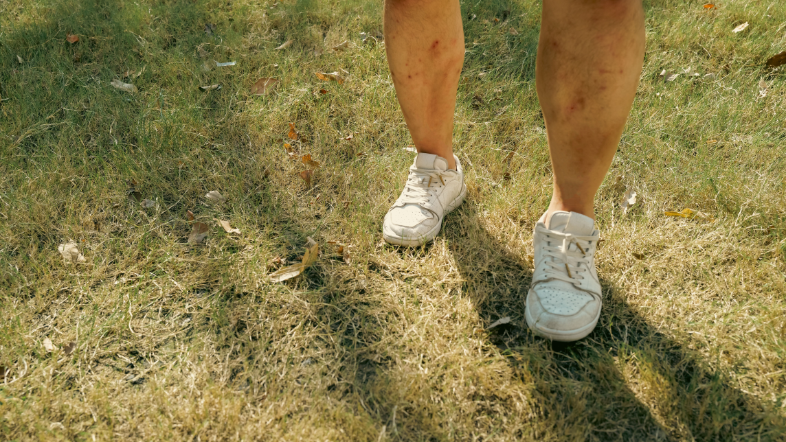 a person (cropped from knees down) standing on grass