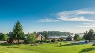 the Maple Ridge museum in the distance on a sunny day with large green grass area and blue sky with a light cloud