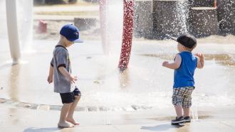 two young children playing in a spray park
