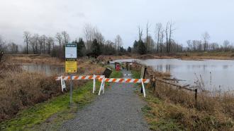 Two wooden barricades prevent parkgoers from going down a flooded path at Jerry Sulina Park.